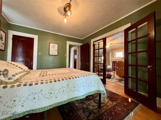 bedroom with a textured ceiling, wood-type flooring, and crown molding