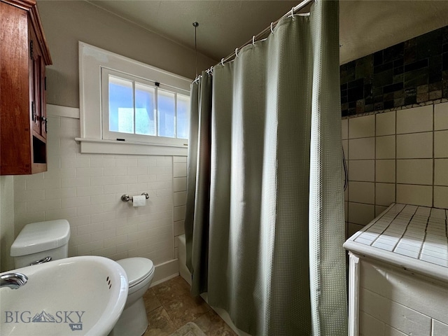 full bathroom with tile walls, shower / bath combo, sink, and toilet