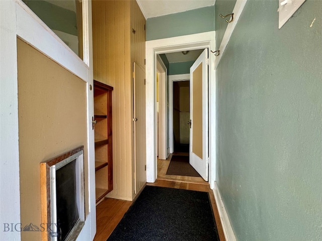 corridor with wooden walls and hardwood / wood-style flooring