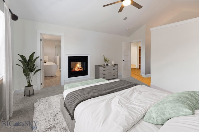 carpeted bedroom with connected bathroom, lofted ceiling, ceiling fan, and a multi sided fireplace