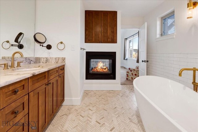 bathroom with a bath, a multi sided fireplace, and vanity