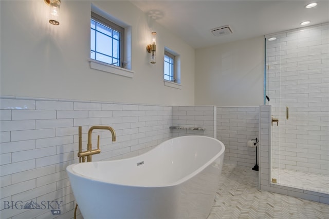 bathroom with independent shower and bath, tile walls, and tile patterned floors