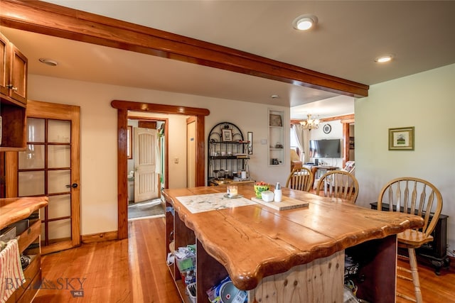 dining room with light wood-type flooring, beam ceiling, and a notable chandelier