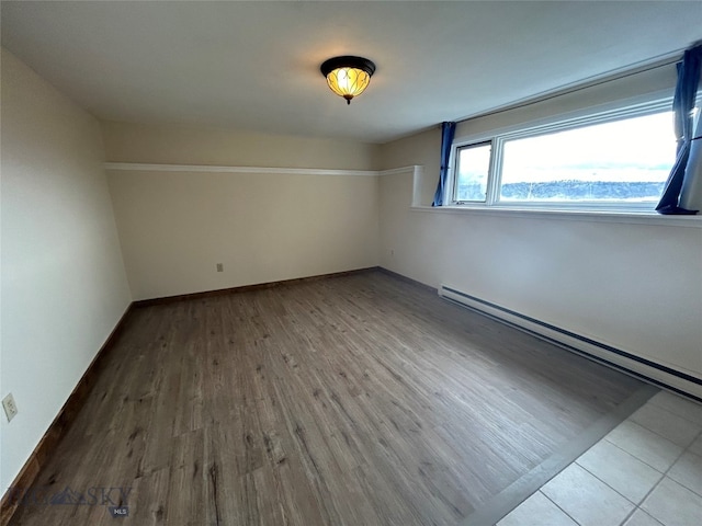 empty room with hardwood / wood-style floors and baseboard heating