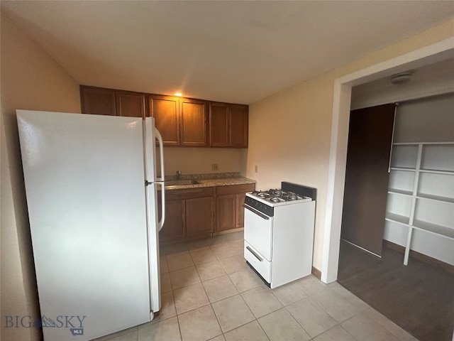 kitchen with white appliances, sink, and light tile patterned floors