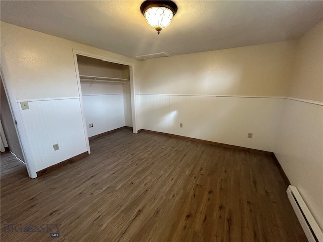 unfurnished bedroom with dark wood-type flooring, a closet, and a baseboard radiator