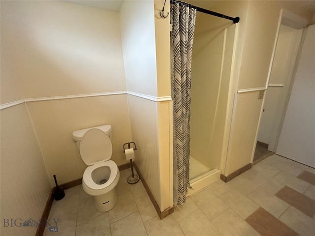 bathroom featuring toilet, a shower with curtain, and tile patterned floors