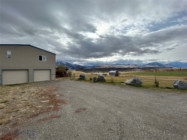 view of yard featuring a mountain view, a rural view, and a garage