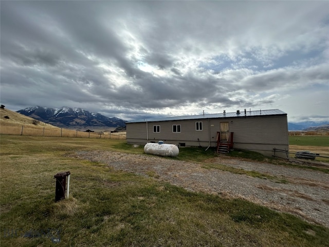 back of house with a mountain view, a rural view, and a lawn