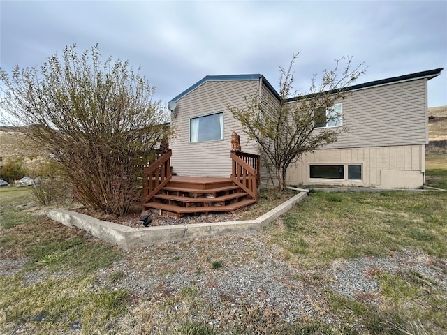 rear view of house featuring a lawn and a wooden deck