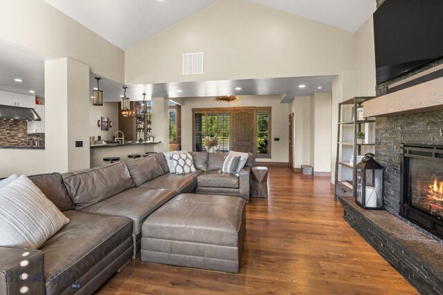 living room with a fireplace, sink, dark wood-type flooring, and high vaulted ceiling