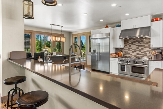 kitchen featuring ventilation hood, white cabinetry, pendant lighting, and high quality appliances