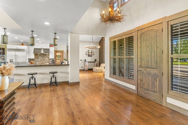 interior space with stainless steel built in refrigerator, white cabinets, a notable chandelier, and hanging light fixtures