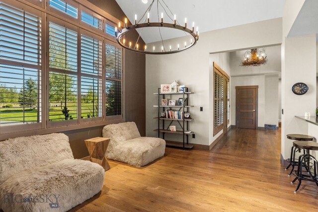 sitting room with an inviting chandelier, high vaulted ceiling, and hardwood / wood-style floors