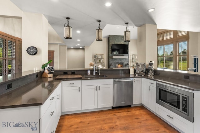 kitchen featuring pendant lighting, stainless steel appliances, kitchen peninsula, and white cabinetry