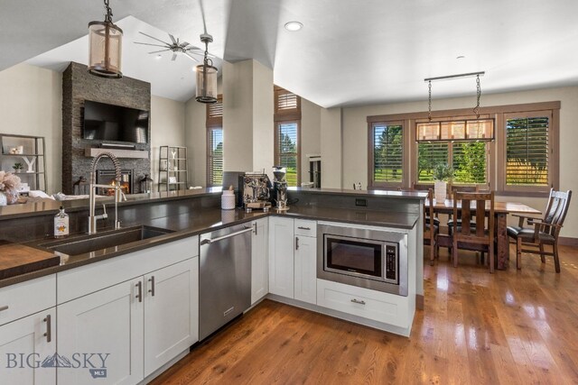 kitchen featuring a fireplace, white cabinets, stainless steel appliances, and decorative light fixtures