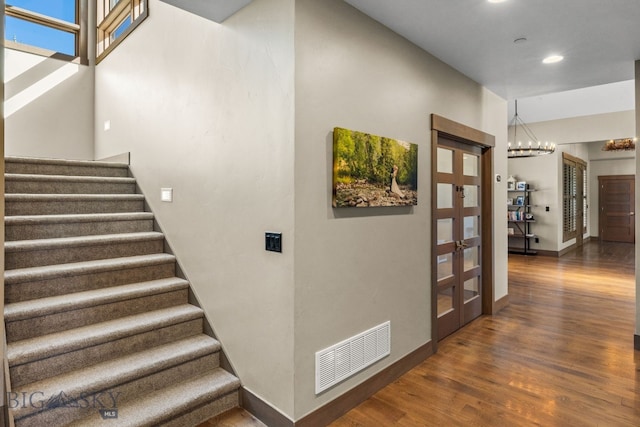 stairs featuring a notable chandelier and wood-type flooring