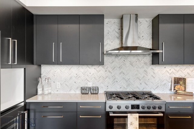 kitchen with stainless steel range, wall chimney exhaust hood, and tasteful backsplash