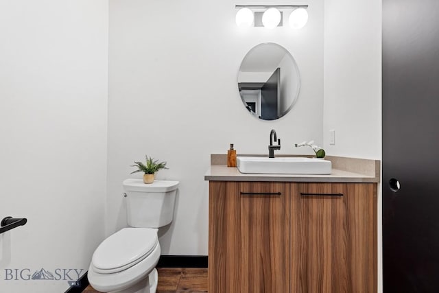 bathroom featuring vanity, baseboards, wood finished floors, and toilet