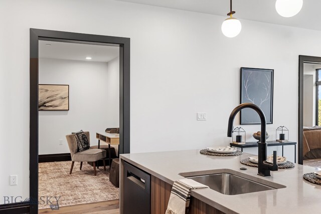 kitchen with wood-type flooring, dishwasher, hanging light fixtures, and sink