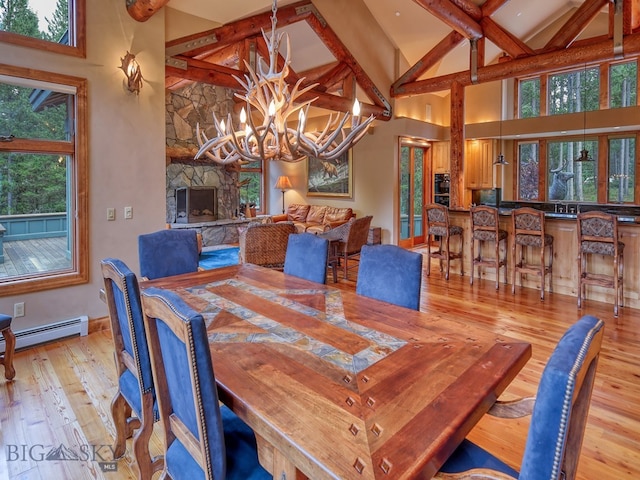 dining area featuring a baseboard radiator, high vaulted ceiling, light hardwood / wood-style flooring, and plenty of natural light