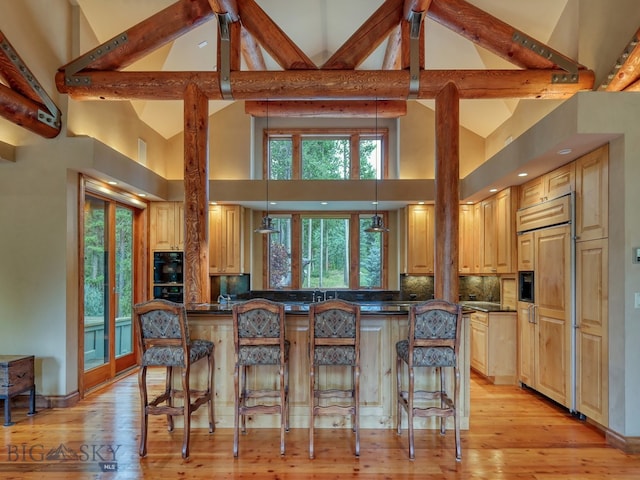 kitchen featuring beam ceiling, high vaulted ceiling, pendant lighting, and light hardwood / wood-style floors