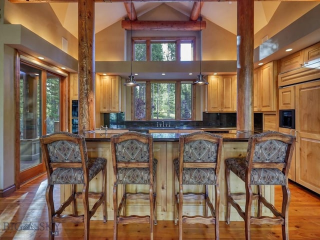 3686 Pinewood Dr, Big Sky, MT 59716 - kitchen featuring dark countertops, paneled refrigerator, a breakfast bar, high vaulted ceiling, and light wood-style floors