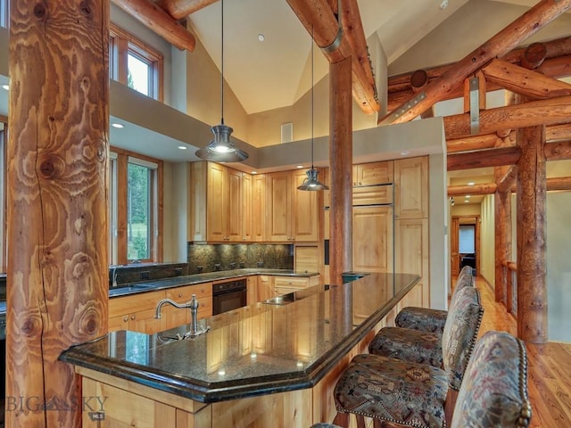 3686 Pinewood Dr, Big Sky, MT 59716 - kitchen with black oven, light wood-type flooring, a spacious island, backsplash, and a kitchen bar