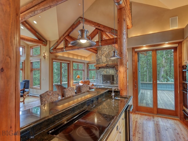 kitchen with black appliances, light hardwood / wood-style floors, ceiling fan, dark stone counters, and high vaulted ceiling