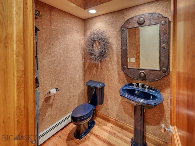 bathroom with baseboard heating, sink, hardwood / wood-style flooring, and toilet