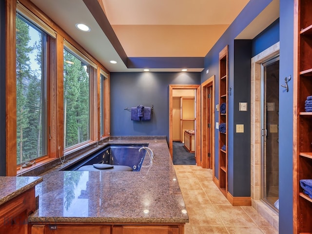 kitchen featuring a wealth of natural light, light tile patterned floors, and dark stone countertops