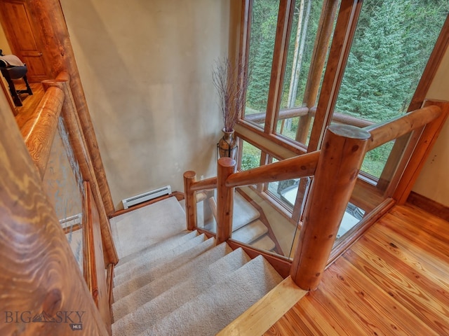 stairs featuring hardwood / wood-style floors and a baseboard heating unit