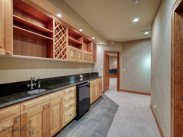 kitchen featuring sink, dark stone countertops, carpet, and black fridge