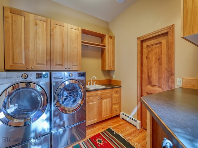 clothes washing area with baseboard heating, sink, cabinets, washing machine and clothes dryer, and light hardwood / wood-style floors