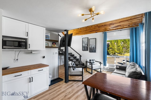 kitchen with white cabinetry, an inviting chandelier, light hardwood / wood-style floors, and wood counters