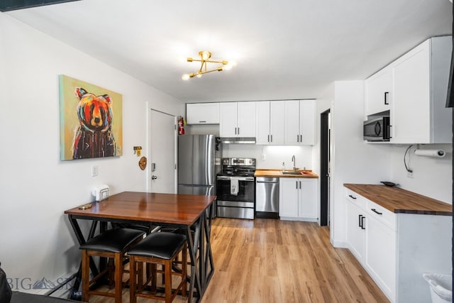 kitchen with sink, appliances with stainless steel finishes, light hardwood / wood-style flooring, white cabinets, and butcher block countertops