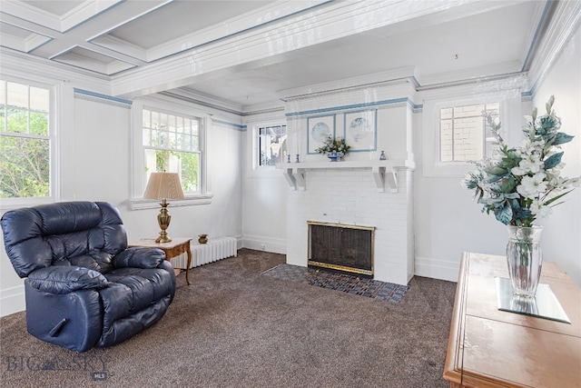 sitting room with a brick fireplace, beamed ceiling, radiator heating unit, dark carpet, and ornamental molding