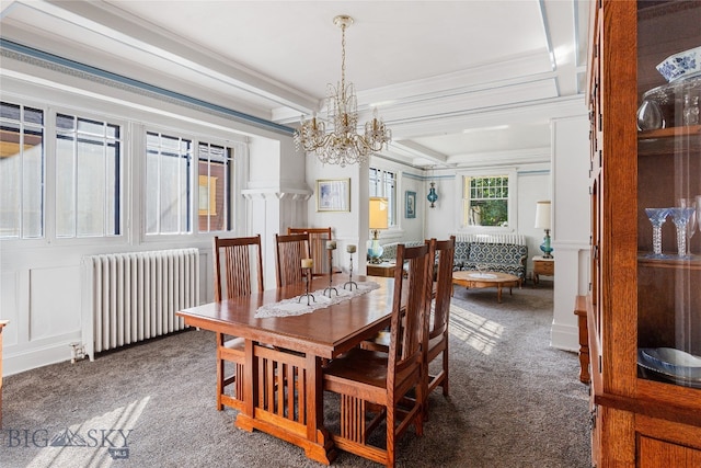 carpeted dining room with radiator, an inviting chandelier, a raised ceiling, and ornamental molding