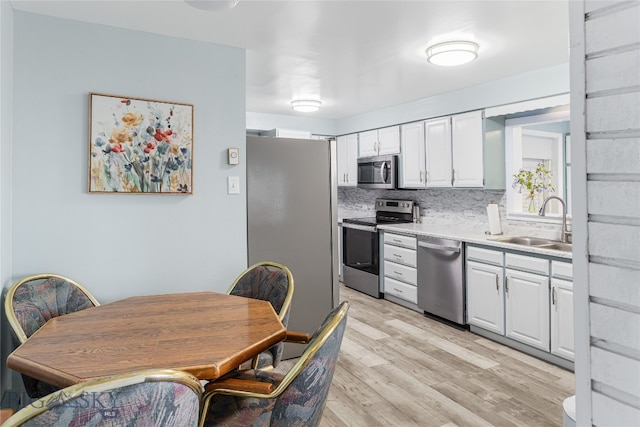 kitchen with tasteful backsplash, light hardwood / wood-style flooring, stainless steel appliances, and white cabinets