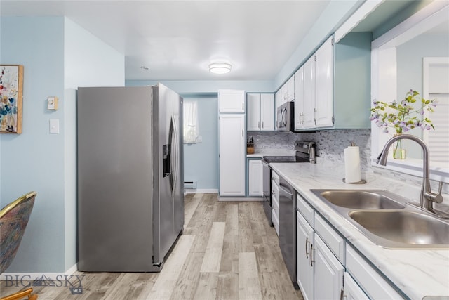 kitchen featuring appliances with stainless steel finishes, sink, light hardwood / wood-style flooring, and white cabinets