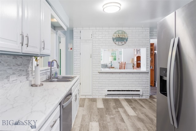 kitchen with white cabinets, sink, light hardwood / wood-style flooring, appliances with stainless steel finishes, and a baseboard radiator