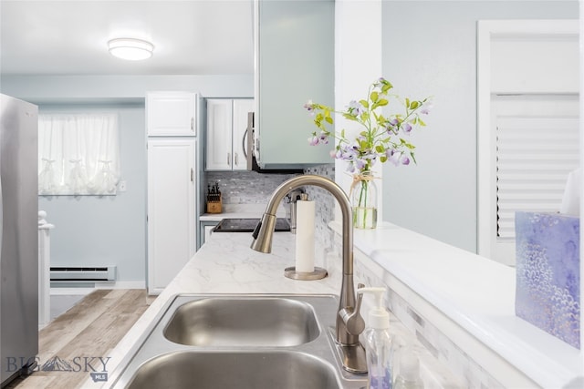 kitchen featuring a baseboard heating unit, light stone counters, tasteful backsplash, sink, and white cabinets