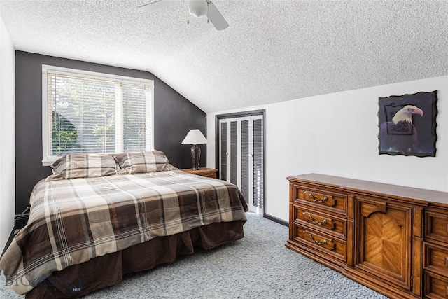 carpeted bedroom with a closet, lofted ceiling, ceiling fan, and a textured ceiling