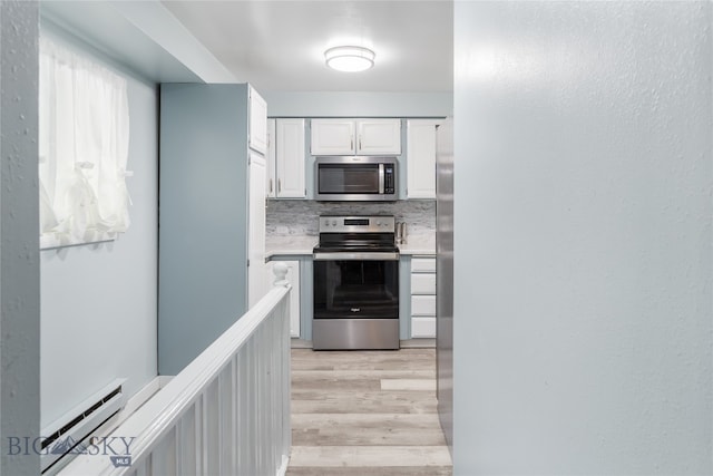 kitchen with tasteful backsplash, a baseboard heating unit, white cabinetry, appliances with stainless steel finishes, and light wood-type flooring