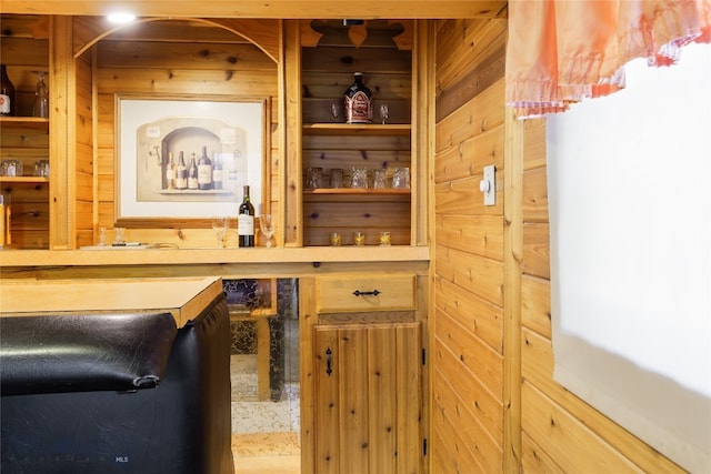 bar featuring wood walls and light brown cabinetry