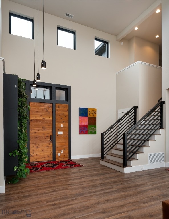 foyer entrance with a wealth of natural light, a towering ceiling, and dark hardwood / wood-style flooring