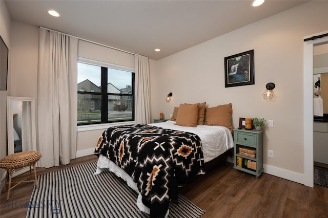 bedroom with dark wood-type flooring and a barn door