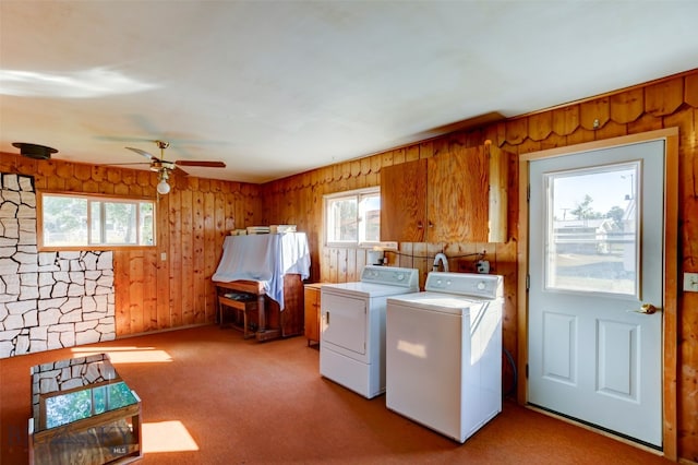 clothes washing area featuring ceiling fan, light colored carpet, wood walls, and independent washer and dryer