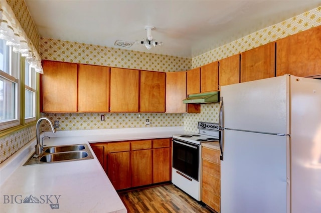 1112 Pritchard NW, Harlowton, MT 59036 - kitchen featuring white appliances, a sink, under cabinet range hood, light countertops, and brown cabinetry