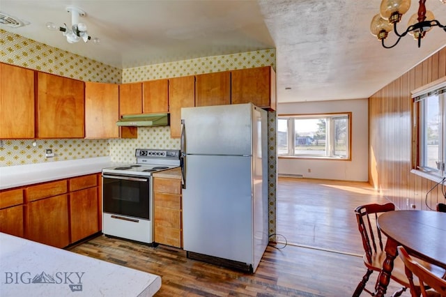 1112 Pritchard NW, Harlowton, MT 59036 - kitchen featuring freestanding refrigerator, white electric range oven, under cabinet range hood, a chandelier, and healthy amount of natural light